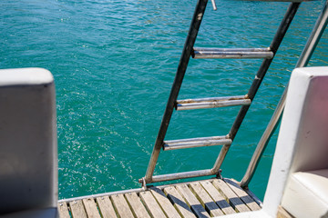 stainless steel iron staircase on the wooden deck of a pleasure boat in the black sea, on a sunny day.