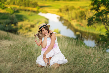 Beautiful young woman playing with her child on the green grass. Mom and little girl shares love. Mothers day