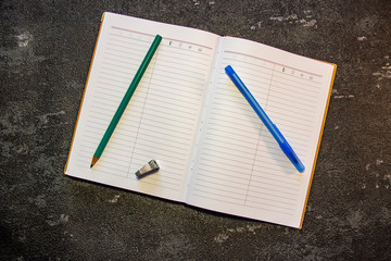 Pen and pencil lie on a notebook, view from the top. Self-adhesive paper for notation. Scissors and...
