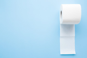 Soft, white toilet paper roll on light pastel blue background. Hygiene concept. Empty place for text, object or logo.