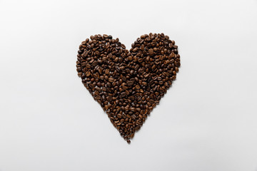 top view of heart made of fresh coffee grains on white background
