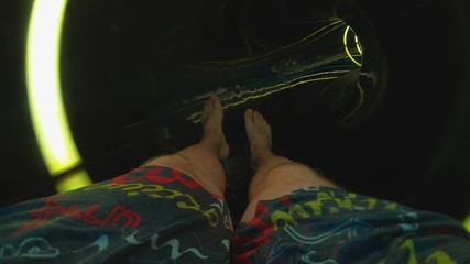 A young man slides down a water slide in a water park. Water pipe to go down. Summer holidays with friends