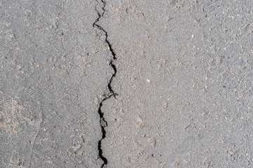 Fototapeta na wymiar Cracks in the old gray asphalt. Abstract background