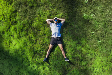 A man lies on a green moss in the forest. View from above.