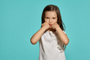 Close-up studio shot of beautiful brunette little girl posing against a blue background.