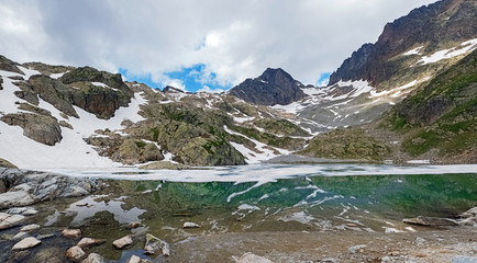 Beautiful high mountain lake in French Alps with turquoise water and covered with snow in some places. Lac Blanc panorama
