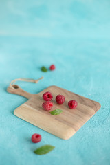 Maliny na drewnianej desce na niebieskim tle © Aga
