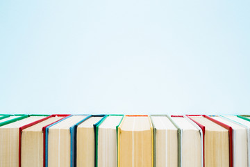 Row of old books with colorful covers on pastel blue background. Education concept. Mock up for...
