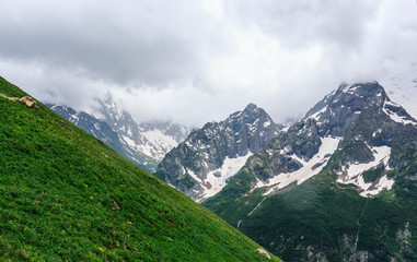 Fototapeta na wymiar Dombay mountain range in the Caucasus in summer, snow-capped peaks and green mountain slopes