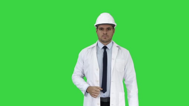 Science engineer in helmet showing stop sing and then makes an attention gesture on a Green Screen, Chroma Key.