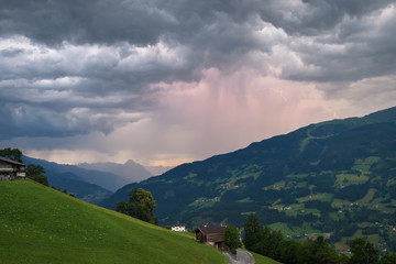 Fototapeta na wymiar Evening thunderstorm in the Alps. Rain shaft is illuminated by lightning.