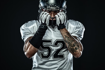 American football sportsman player in helmet isolated on black background. Sport and motivation...
