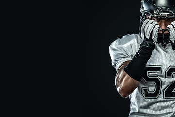American football sportsman player in helmet isolated on black background. Sport and motivation...