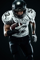 American football sportsman player in helmet isolated run in action on black background. Sport and motivation wallpaper.