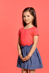 Close-up studio shot of beautiful brunette little girl posing against a blue background.