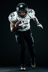Fototapeta na wymiar American football sportsman player in helmet isolated run in action on black background. Sport and motivation wallpaper.