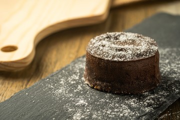 Chocolate fondant with icing sugars on top, on a black slate plate, selective focus