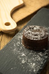 Chocolate fondant with icing sugars on top, on a black slate plate, selective focus
