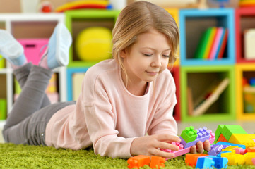 Portrait of little girl playing with colorful plastic blocks