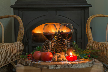 Cozy interior with burning stove, two glass of wine and fruits of tree stump in the dark