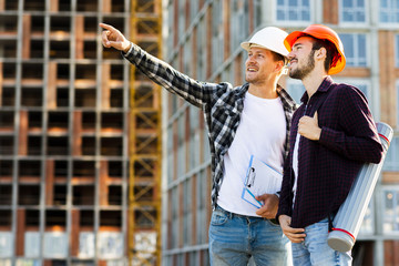 Medium shot side view of engineer and architect supervising construction
