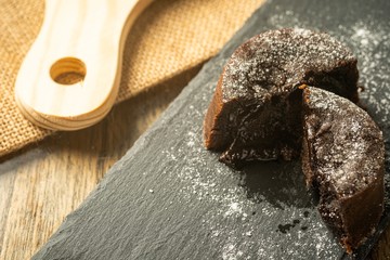 Chocolate fondant with icing sugars on top, on a black slate plate, selective focus
