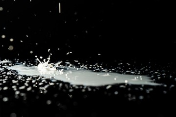 Milk spilled on black surface, closed up, selective focus