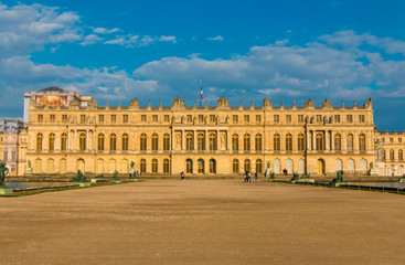 Fototapeta na wymiar Perfect sunset panoramic view of the west facade of Versailles palace from the Water Parterre with two rectangular pools and a gravel path in the centre. The palace is a UNESCO World Heritage Site.