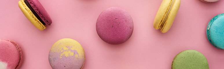 pattern of multicolored delicious French macaroons scattered on pink background, panoramic shot