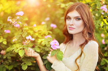 Fototapeta premium Portrait of beautiful young woman posing by rose bush