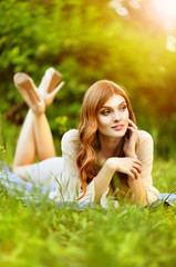 Beautiful young woman lying on green meadow