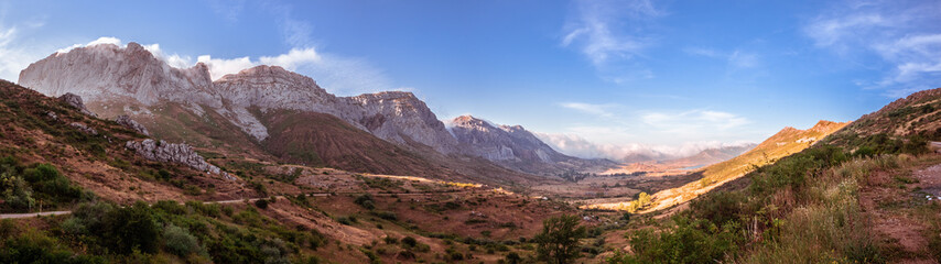 Fototapeta premium Panoramic sunset in the valley of Arbas in Leon, Spain, with clouds passing over the peaks towards the valley
