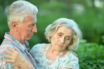 unhappy senior couple posing in the summer park