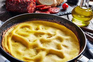 omelette in a skillet served with sliced chorizo