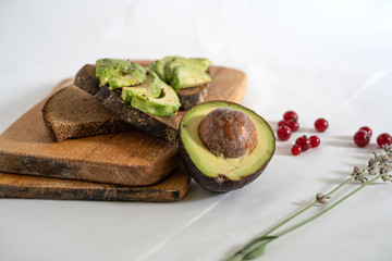 on a white background on an chopped wooden board avocado cut in half and half, avocado sandwich, horizontal frame, copy space