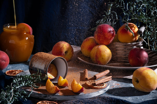 interesting picture still life with a group of peaches, a jar of flowing juice and particles of crumbling cinnamon. Art photography in rustic style