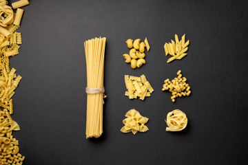 Assorted types of pasta on black background. Top view. Various forms of pasta. Copy space for...
