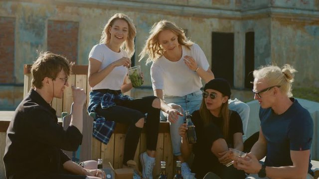Group of Stylish Girls and Boys Drinking Craft Drinks and Eating Healthy Take Away Street Food on the Park Bench in Cool Hipster City District