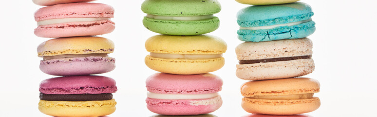 rows of tasty colorful French macaroons of different flavors isolated on white, panoramic shot