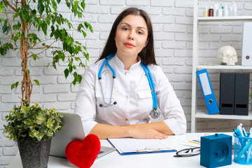 Young female doctor cardiologist sitting at her desk and working