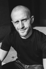 Fototapeta premium Close-up vertical portrait of young smiling man resting looking upwards in low key. Monochrome