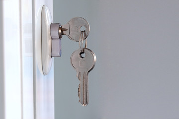 New keys are inserted into the mortise lock. Opening or closing a white plastic door. The concept of forgetfulness and distraction of the landlord or the acquisition of new housing. Copy space.