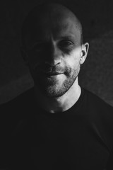 Do you redy to life. Close-up vertical portrait of young smiling man resting looking upwards in low key. Monochrome