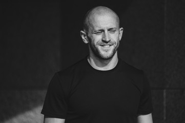 Horizontal portrait of young smiling man resting looking upwards in low key. Monochrome