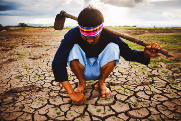 Hopeless and lonely Farmer sitiing on dry ground and finding Living plants. Global warming crisis, ...