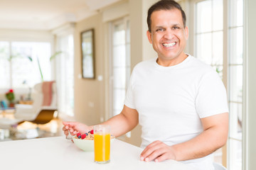 Middle age arab man eating cereals at breakfast with happy face
