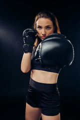 Athletic woman in boxing gloves is practicing karate in studio.