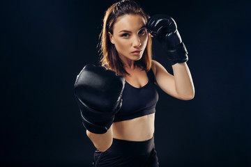 Athletic woman in boxing gloves is practicing karate in studio.