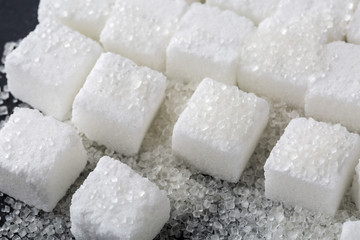 Closeup of granulated and sugar cube on black background