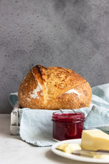 Toasted white artisan bread with butter and jam on light grey stone table. Simple breakfast.